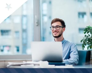 employee smiles as he sits at his desk 