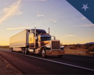black semi truck drives along a desert road