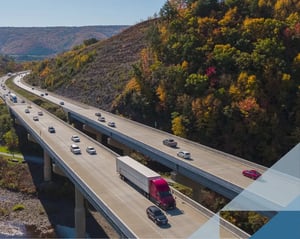 red semi truck drives along a busy highway