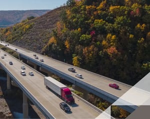 red semi truck drives along a crowded highway