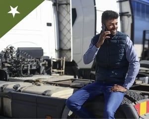 owner operator answers a phone call while sitting on the back of a truck