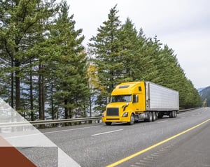 yellow semi truck drives along road