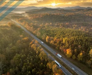 Commercial trucks pass on a highway during sunset