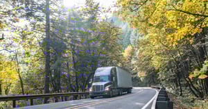 Picturesque view of a semi truck driving on a narrow road with foliage